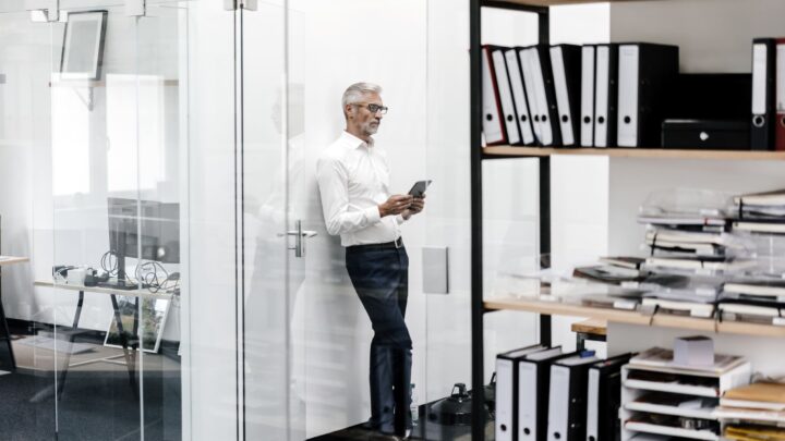 Mężczyzn w biurze opiera się o szklaną ściane